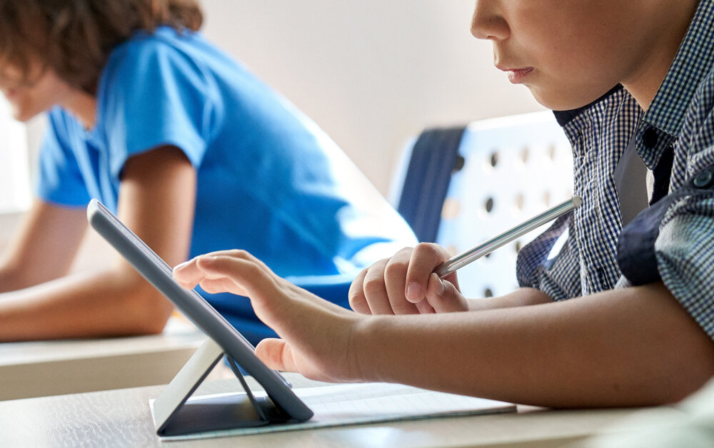 A child uses a tablet for a learning exercise in a classroom.