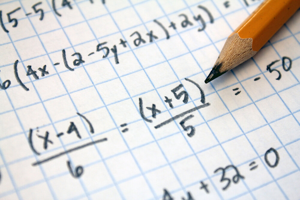 A piece of paper shows handwritten algebra problems.