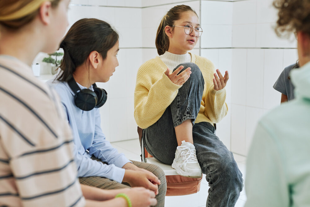 A group of children sit together in a circle talking.